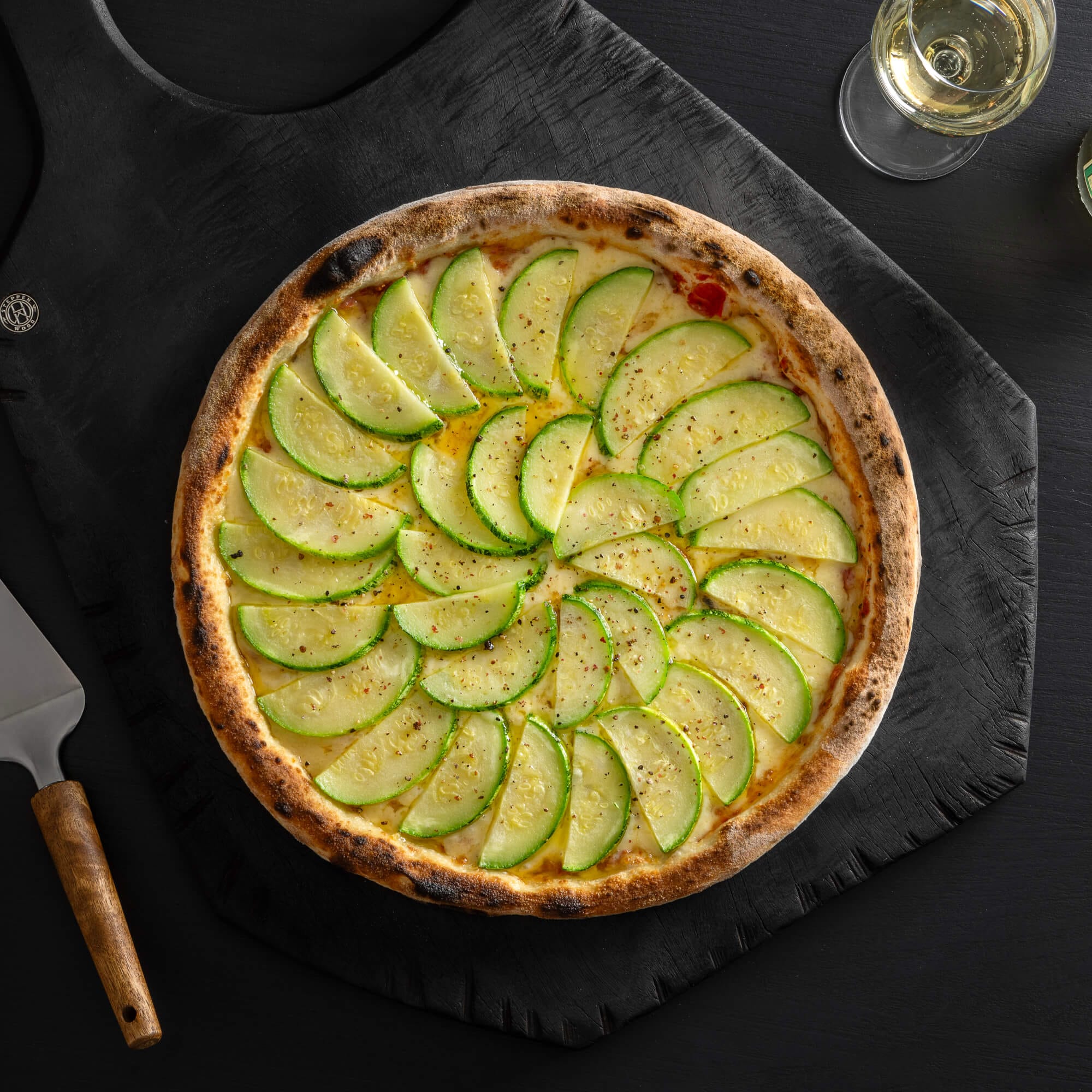 Pizza de abobrinha com massa de fermentação lenta de 48 horas, molho artesanal, queijo derretido, abobrinha fatiada e azeite de alho.