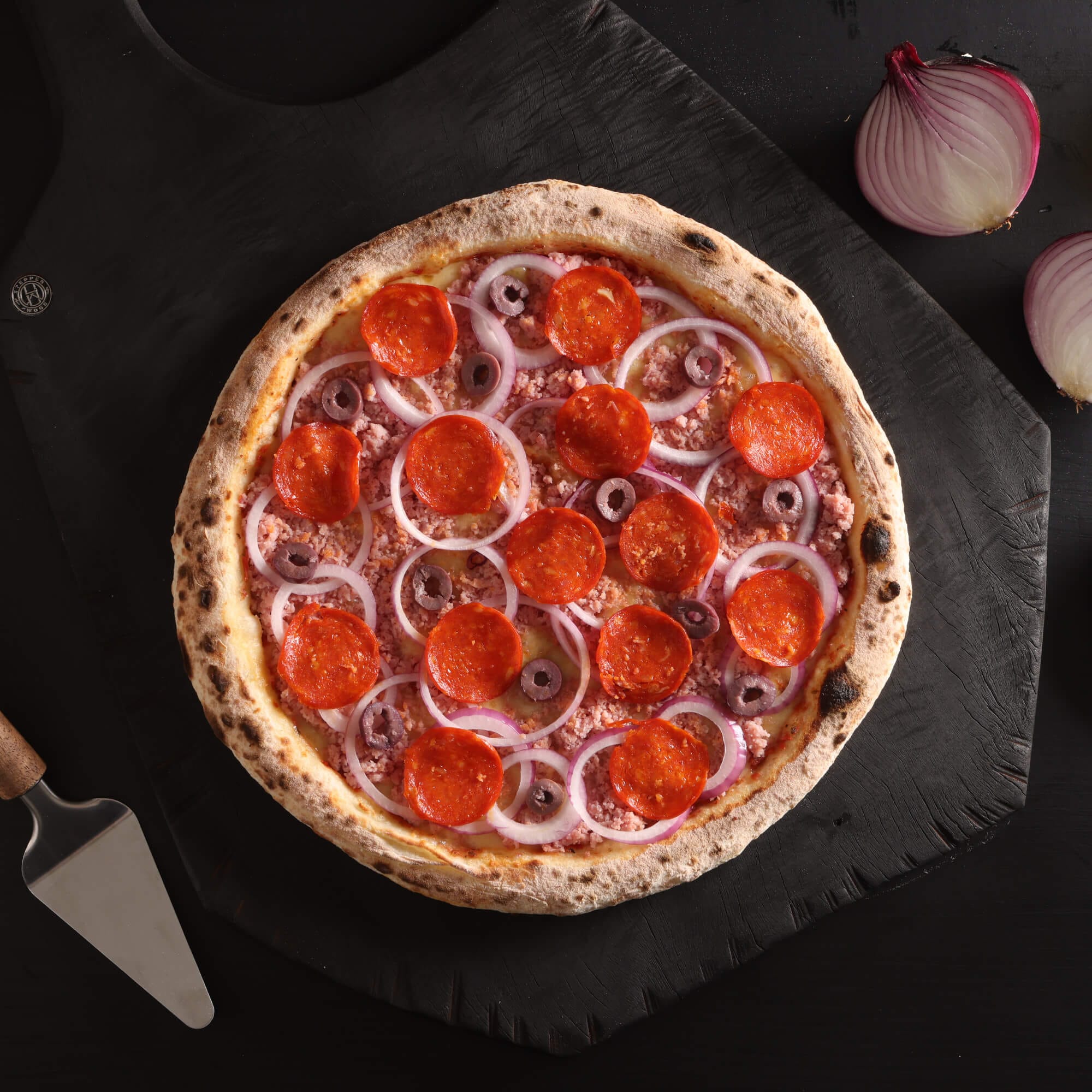Pizza Arpejo com massa de fermentação lenta de 48 horas, molho artesanal, queijo derretido, cebola fatiada, presunto ralado, pepperoni e azeitonas.