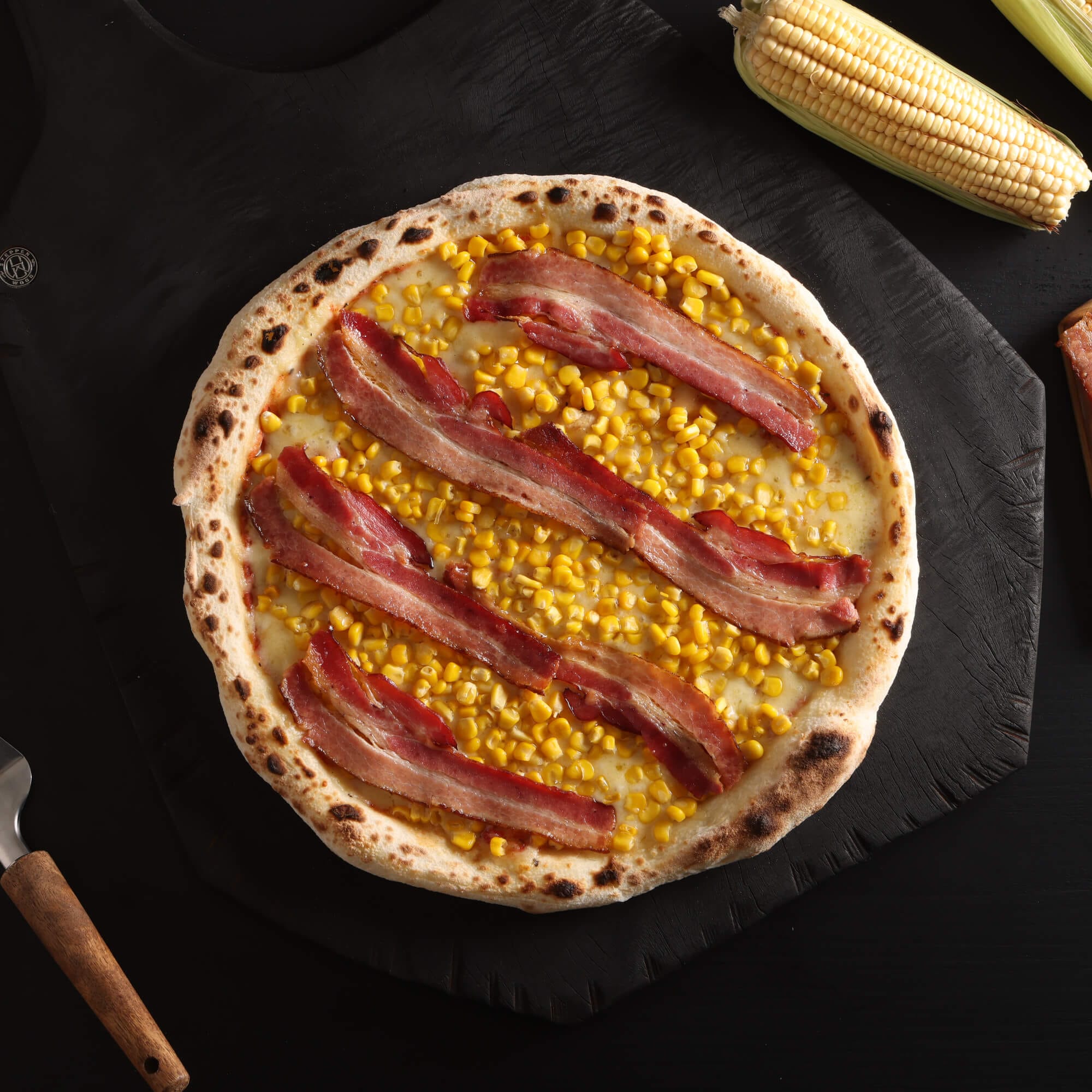 Pizza de milho e bacon com massa de fermentação lenta de 48 horas, molho artesanal, queijo derretido, milho e bacon em fatias.