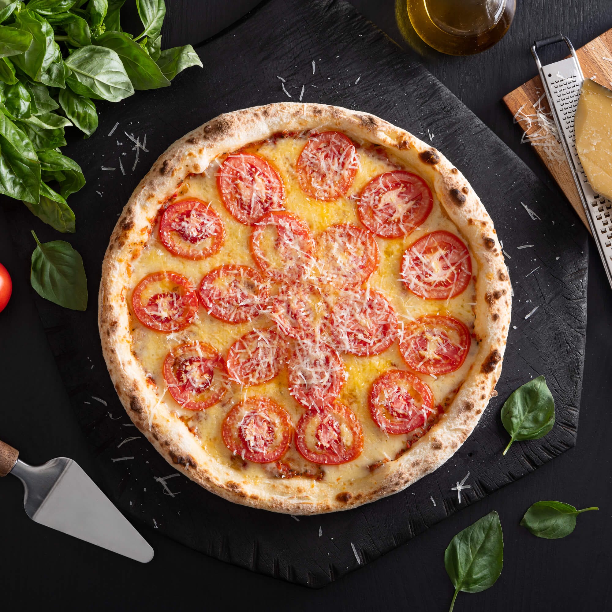 Pizza napolitana artesanal com massa de fermentação lenta de 48 horas, molho de tomate artesanal, queijo derretido, rodelas de tomate fresco e parmesão salpicado.