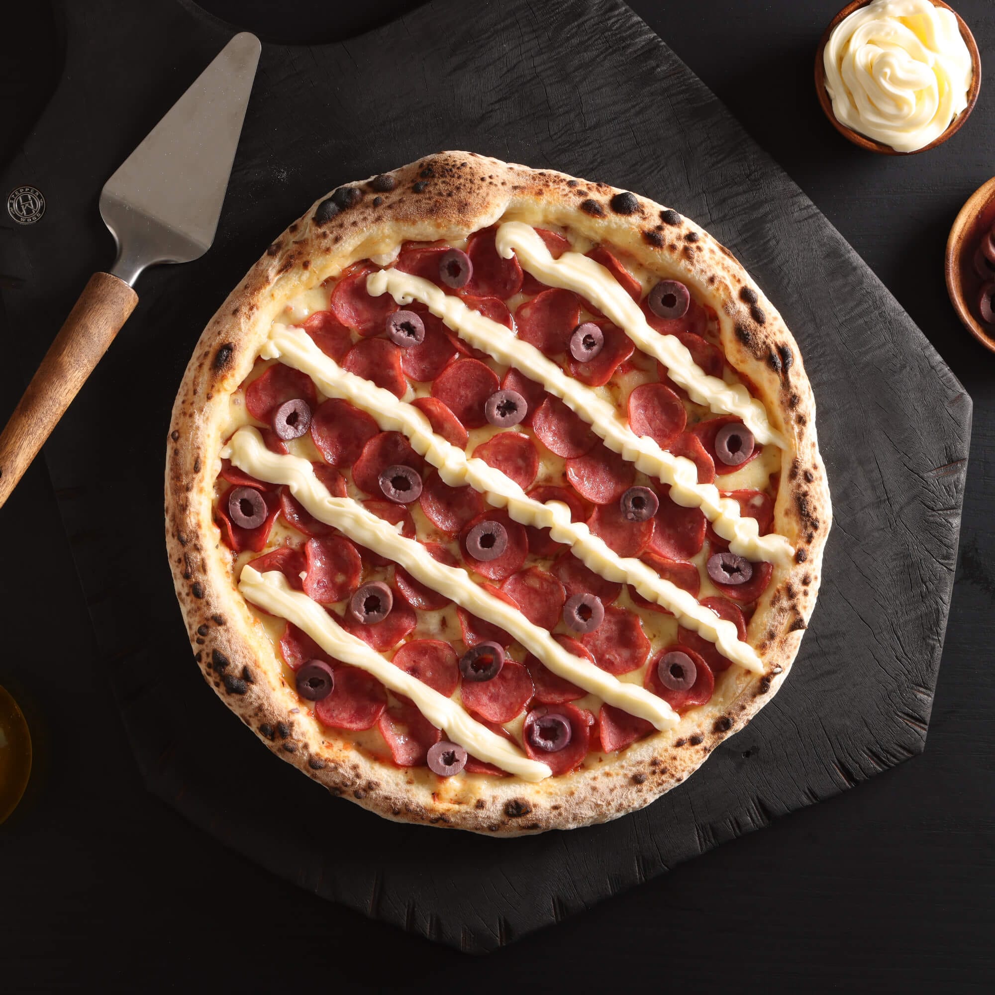 Pizza Rapsódia com massa de fermentação lenta, molho artesanal, queijo, calabresa, requeijão e azeitonas.